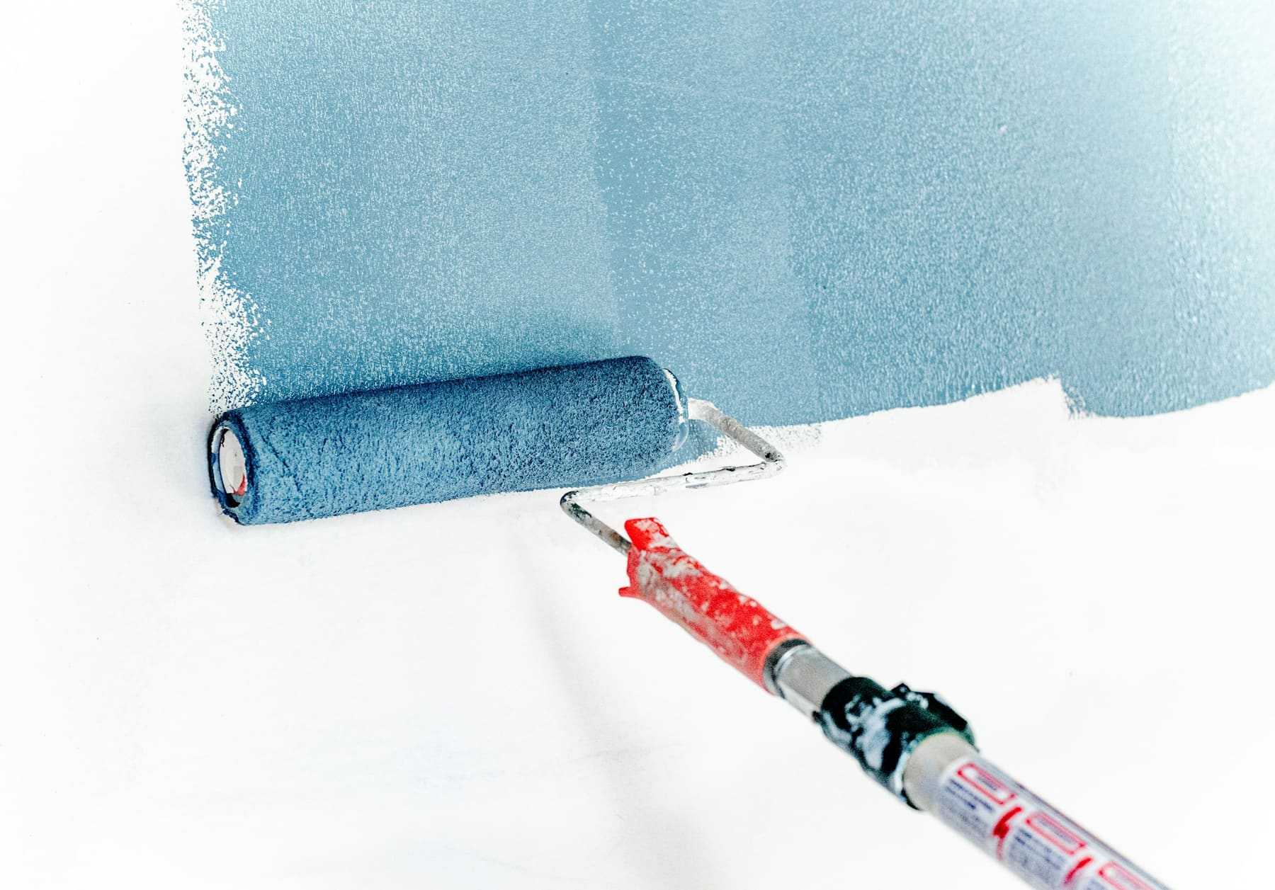 A roller painting a white wall blue